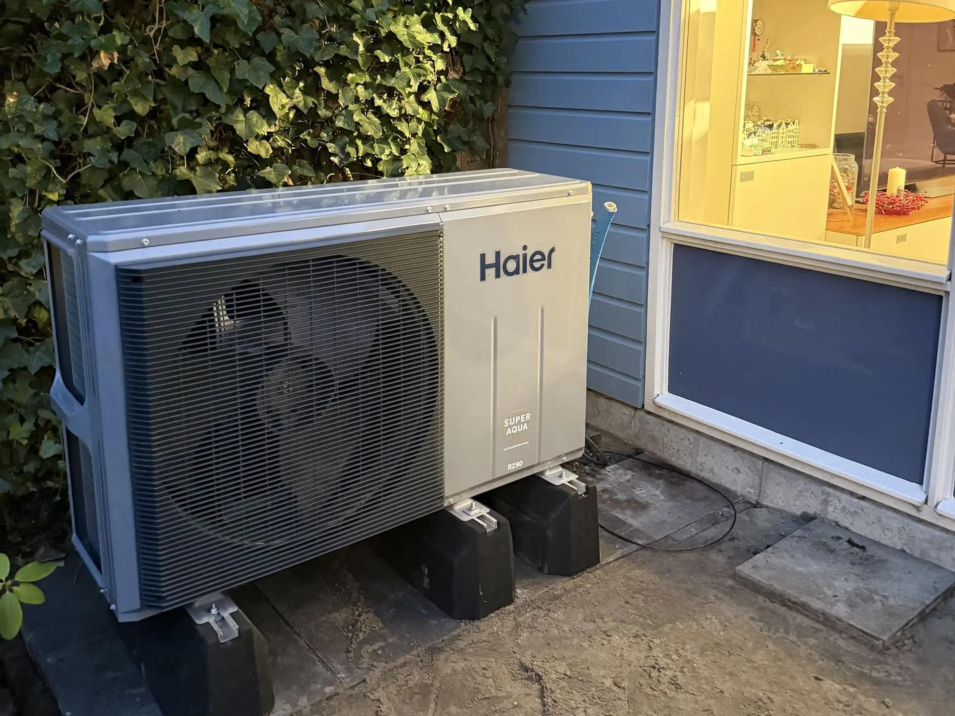 Haier outdoor heat pump unit installed near rooftop solar panels