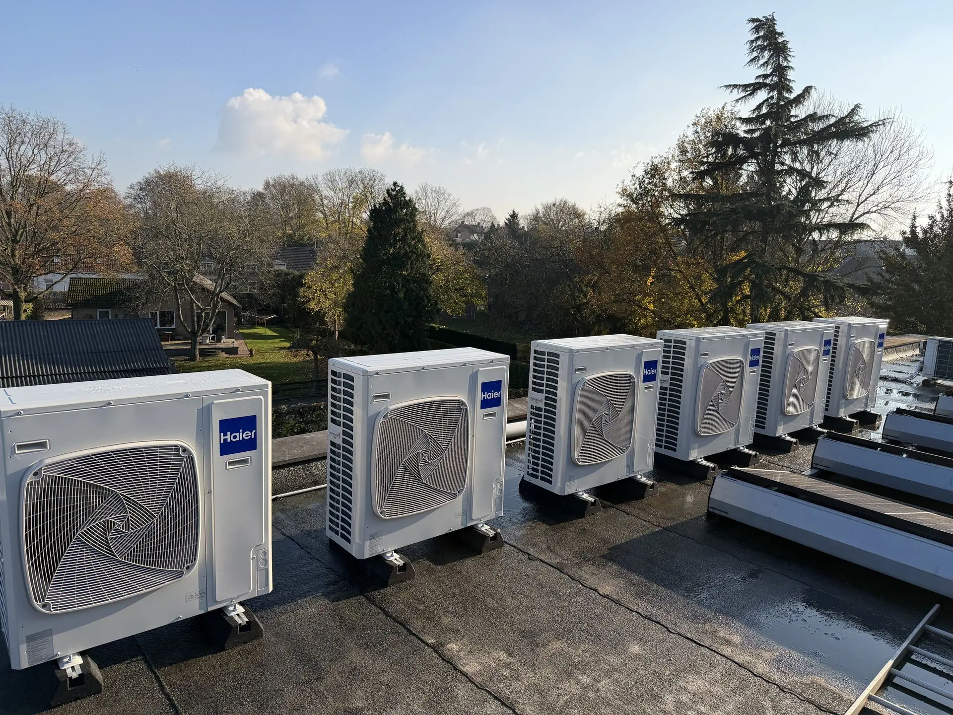 Multiple Haier heat pump outdoor units installed on a flat roof in the Netherlands